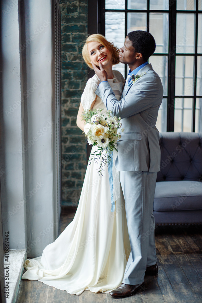 An interracial couple in love embraces at their wedding. African man and white woman An interracial couple in love embraces at their wedding. African man and white woman