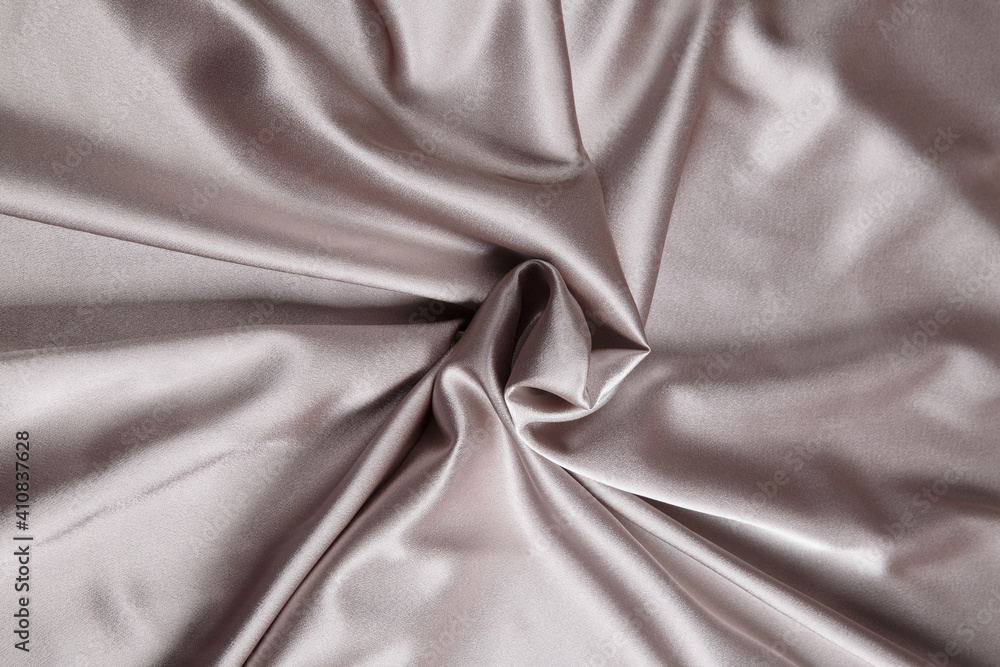 Colored silver textile satin fabric folded in folds and waves with highlights and texture