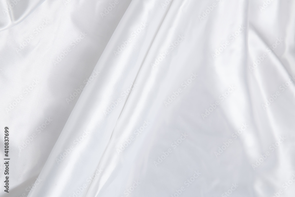 Colored white textile satin fabric folded in folds and waves with highlights and texture