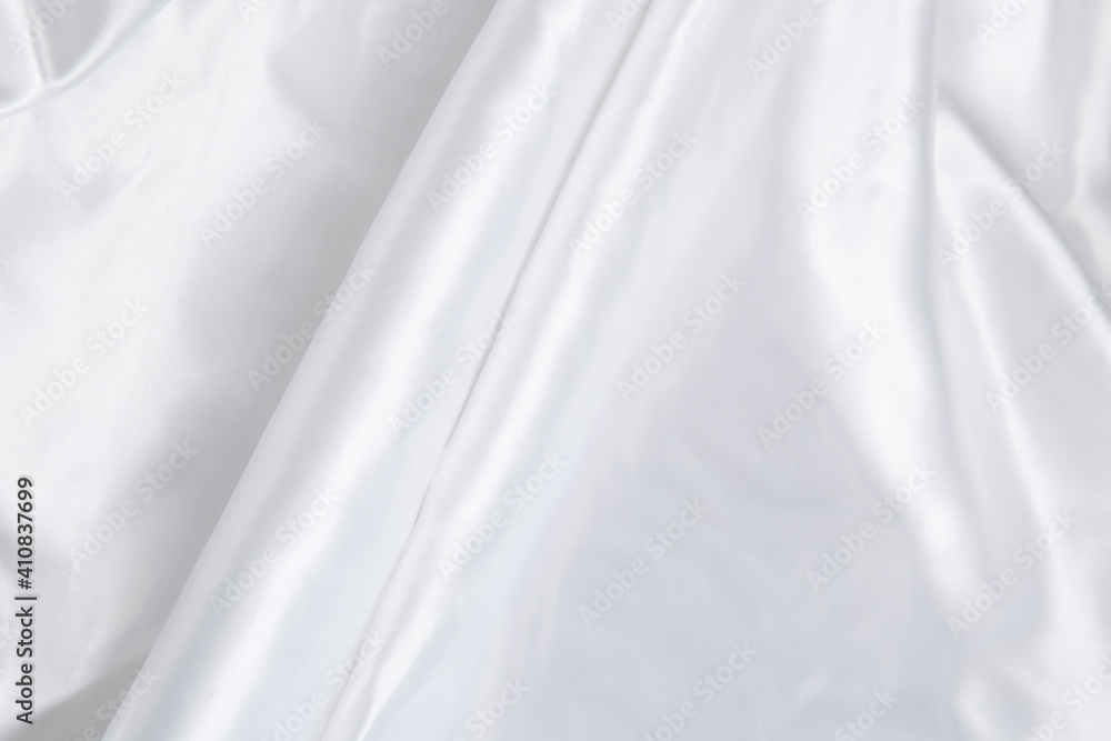 Obraz premium Colored white textile satin fabric folded in folds and waves with highlights and texture