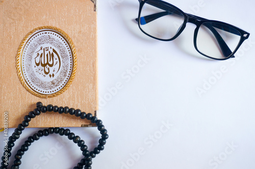 Holy Book of Quran with rosary beads or tasbih and reading glasses on white background. Ramadan concept, Islamic religious ritual