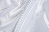 Colored white textile satin fabric folded in folds and waves with highlights and texture