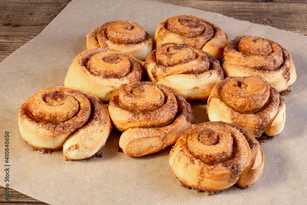 Freshly baked cinnamon buns with spices and cocoa filling on parchment paper. Sweet Homemade Pastry christmas baking. Close-up. Kanelbule - swedish dessert. Freshly baked cinnamon buns with spices and cocoa filling on parchment paper. Sweet Homemade Pastry christmas baking. Close-up. Kanelbule - swedish dessert.