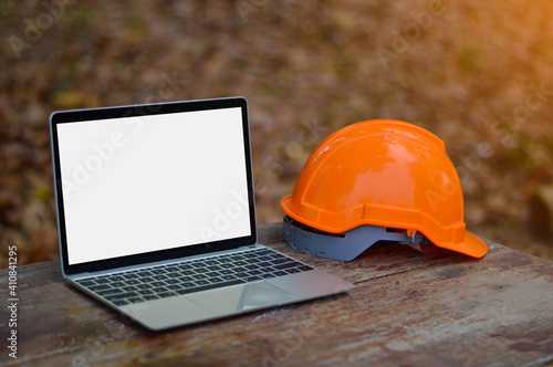 The laptop white screen is placed on the table next to the engineering hat.