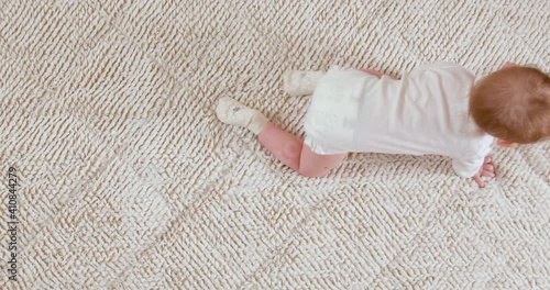 Baby crawling on the white blanket, top view