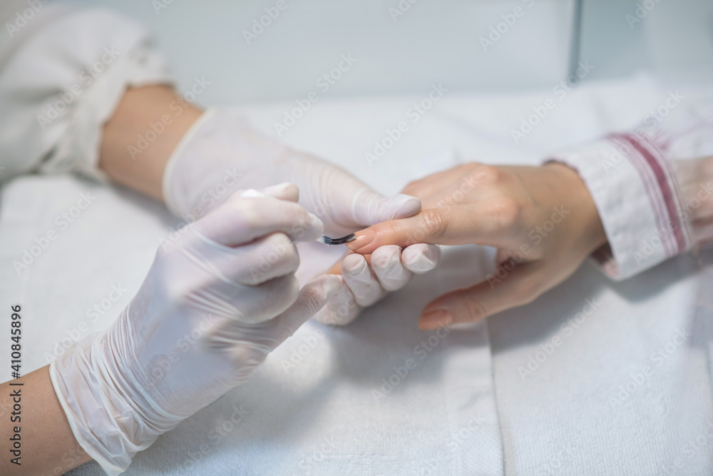 Close up picture of nail artists hands applying nail base Close up picture of nail artists hands applying nail base