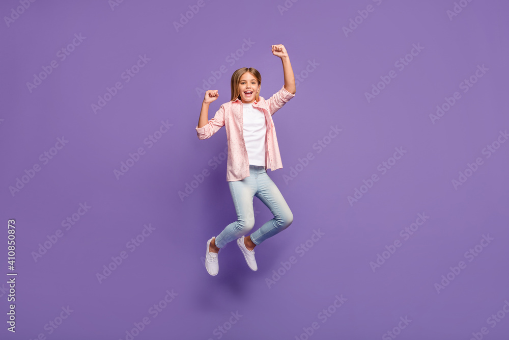 Full size photo of impressed pretty girl jump wear pink shirt jeans sneakers isolated on violet background Full size photo of impressed pretty girl jump wear pink shirt jeans sneakers isolated on violet background