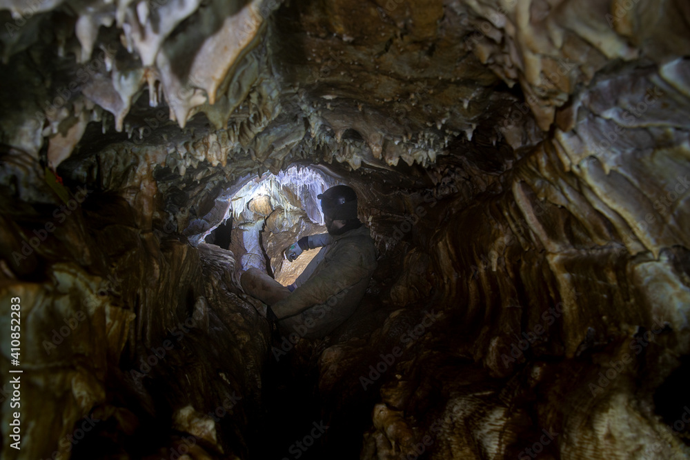 man in cave with lite with stalactites