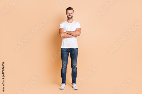 Full length photo of young handsome man happy positive smile confident crossed hands isolated over beige color background