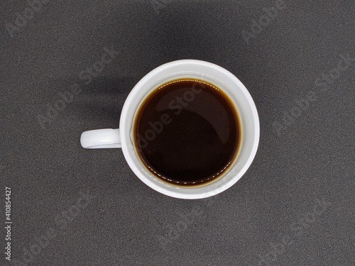 White cup with coffee. White cup of coffee top view. White cup of coffee on a black background top view.