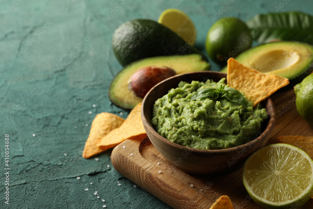 Concept of tasty eating with bowl of guacamole on green textured background Concept of tasty eating with bowl of guacamole on green textured background