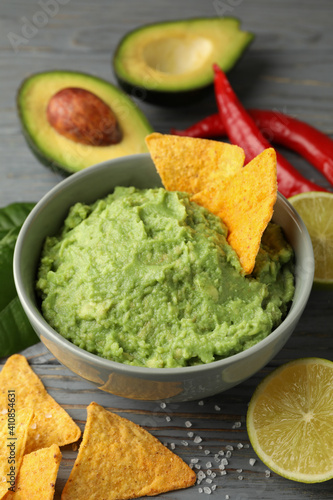 Concept of tasty eating with bowl of guacamole on wooden background