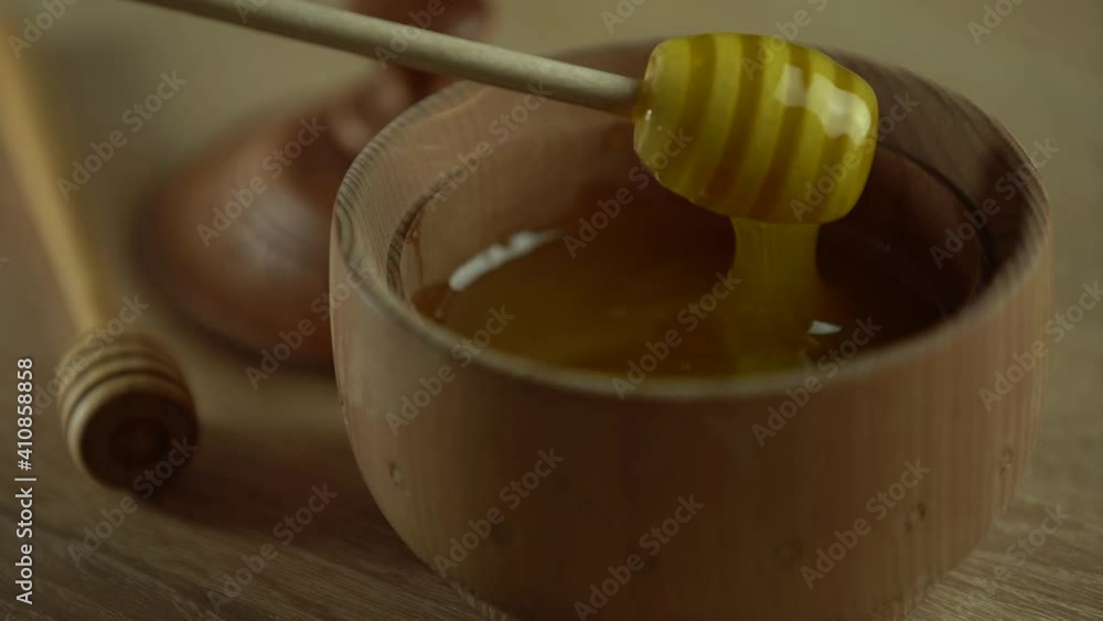 Honey with wooden honey dipper in wooden bowl on wooden table Honey with wooden honey dipper in wooden bowl on wooden table