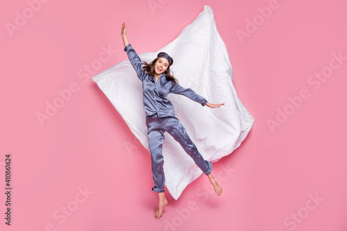 Full length photo portrait of excited girl jumping up isolated on pastel pink colored background with blanket