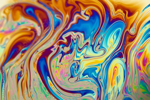Brightly ornamental background with abstract patterns in dominant fiery orange color. Modern liquid art. Mixed colors in soap bubbles, closeup.
