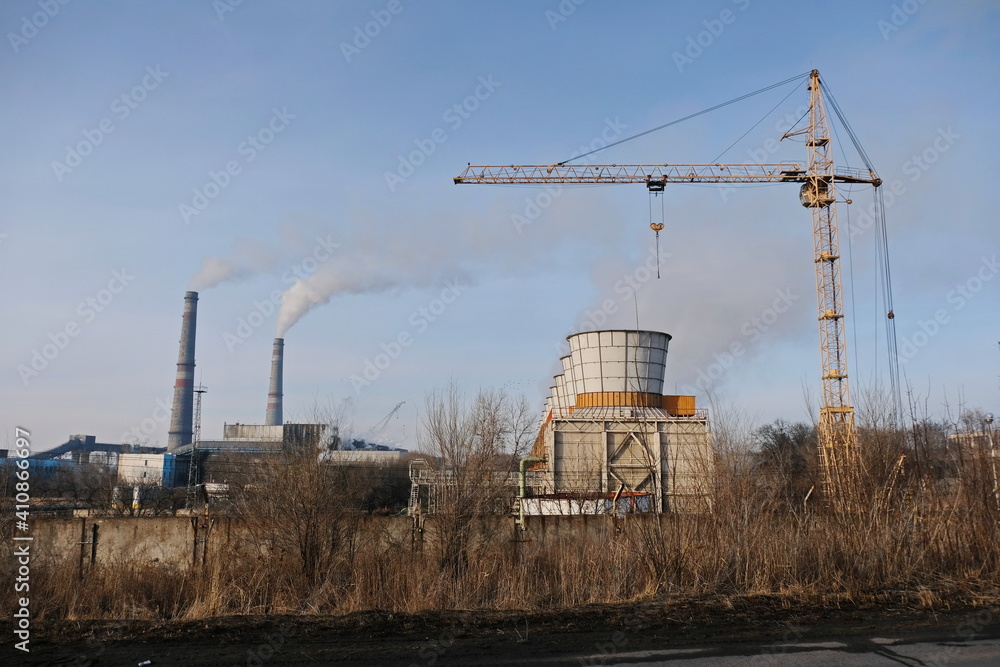 Almaty, Kazakhstan - 02.04.2021 : Cooling tower, Smoking chimneys and tower crane to the district heating Almaty, Kazakhstan - 02.04.2021 : Cooling tower, Smoking chimneys and tower crane to the district heating