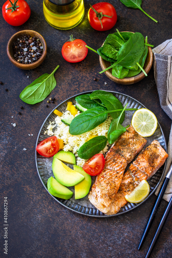 Grilled salmon fillet close-up with couscous, salad fresh vegetables and avocado on dark background. Copy space. Grilled salmon fillet close-up with couscous, salad fresh vegetables and avocado on dark background. Copy space.