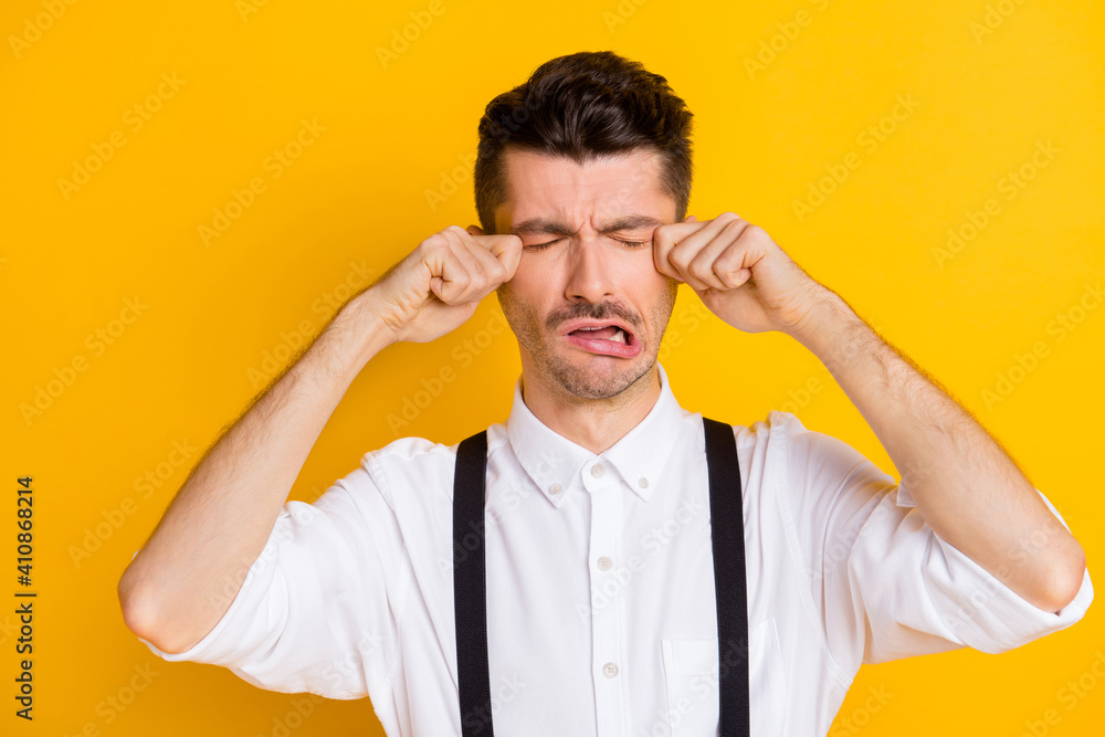 Photo portrait of childish guy grimacing crying tears unhappy sad frustrated touching face isolated on vibrant yellow color background Photo portrait of childish guy grimacing crying tears unhappy sad frustrated touching face isolated on vibrant yellow color background