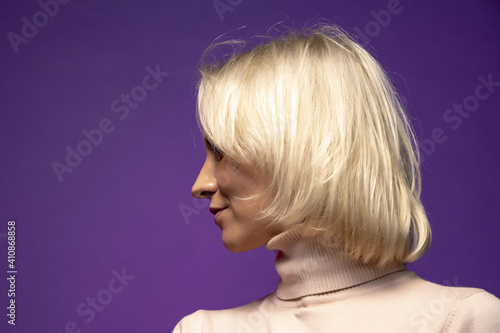 Studio portrait of a smiling blonde woman 25-30 years old on a color background, close-up, selective focus.