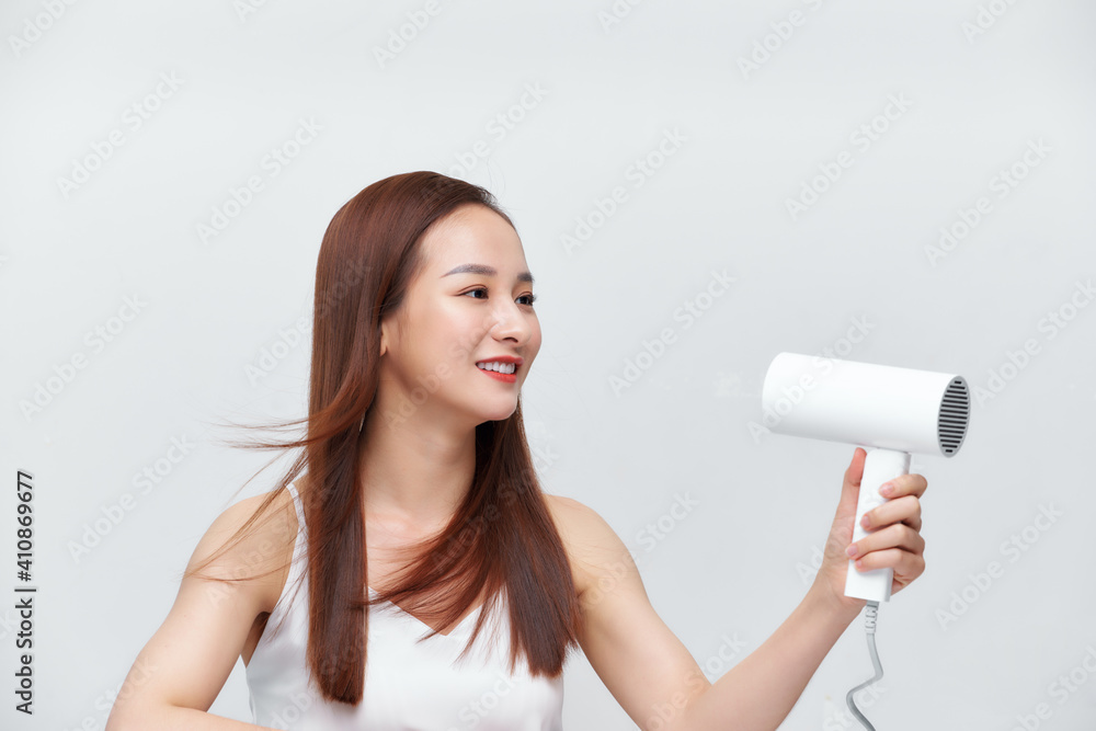 attractive cheerful teenager girl blows dry her hair with hairdryer, over white attractive cheerful teenager girl blows dry her hair with hairdryer, over white