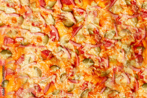 Surface of baked homemade pizza close-up with salami, sausage, cheese, herbs. Background, wallpaper appetizing