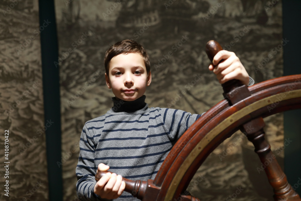 Boy at steering wheel on wall background