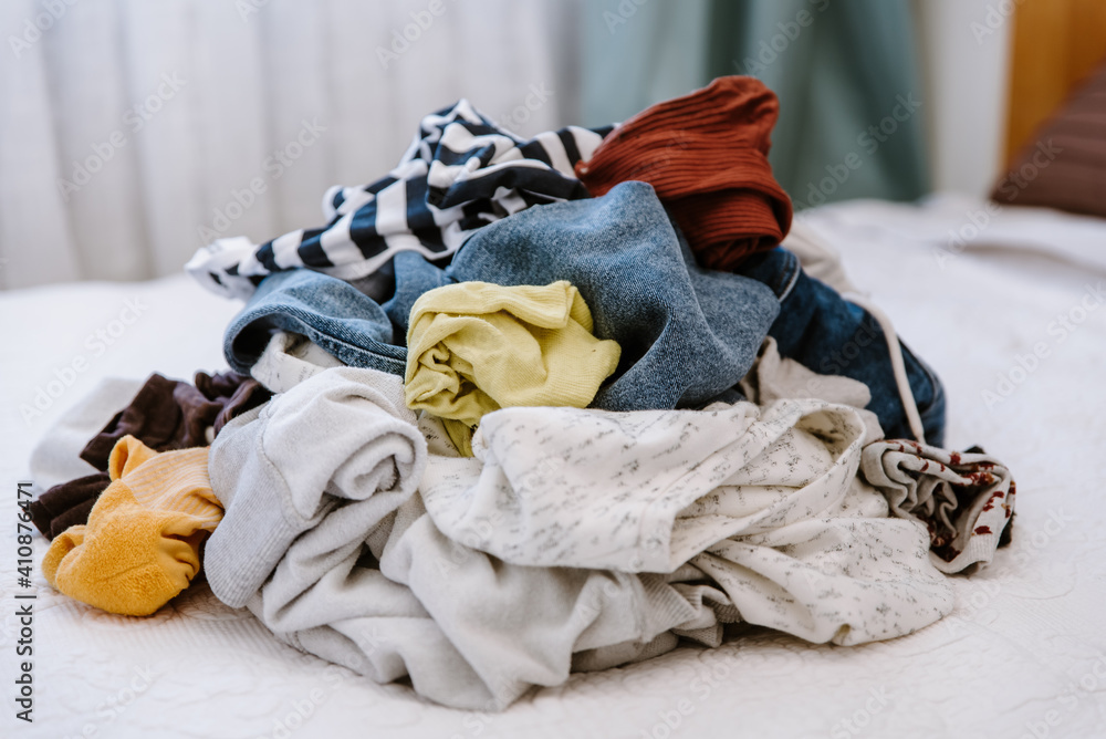 Pile of unfolded dirty clothes for laundry on the bed. Heap of used
