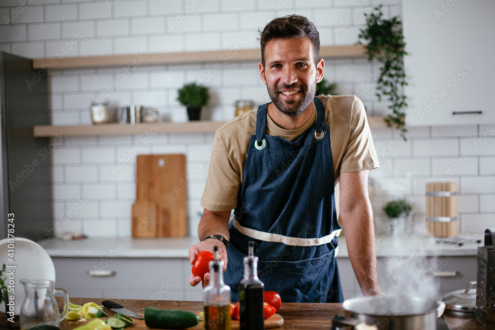 Happy man in kitchen. Young man preparing delicious food Happy man in kitchen. Young man preparing delicious food