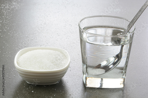 Sugar water in a glass cup and heap of sugar in a bowl. Sugar water is instant energy sports drink, helps in dehydration.