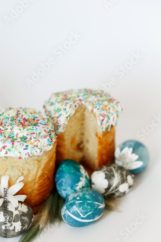 Easter composition with orthodox sweet bread, kulich and eggs on light background. Easter holidays breakfast concept with copy space.