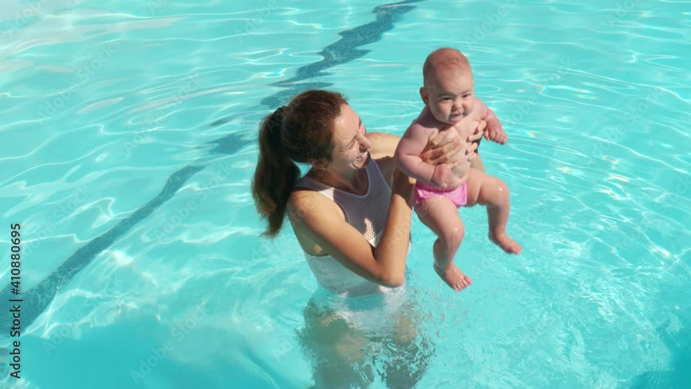 Mother and baby together at pool. Mom supporting infant child at swimming pool water. Mother and baby together at pool. Mom supporting infant child at swimming pool water.
