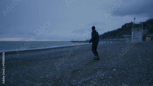 Young tall person is doing warm up. Training on open air at nasty weather photo