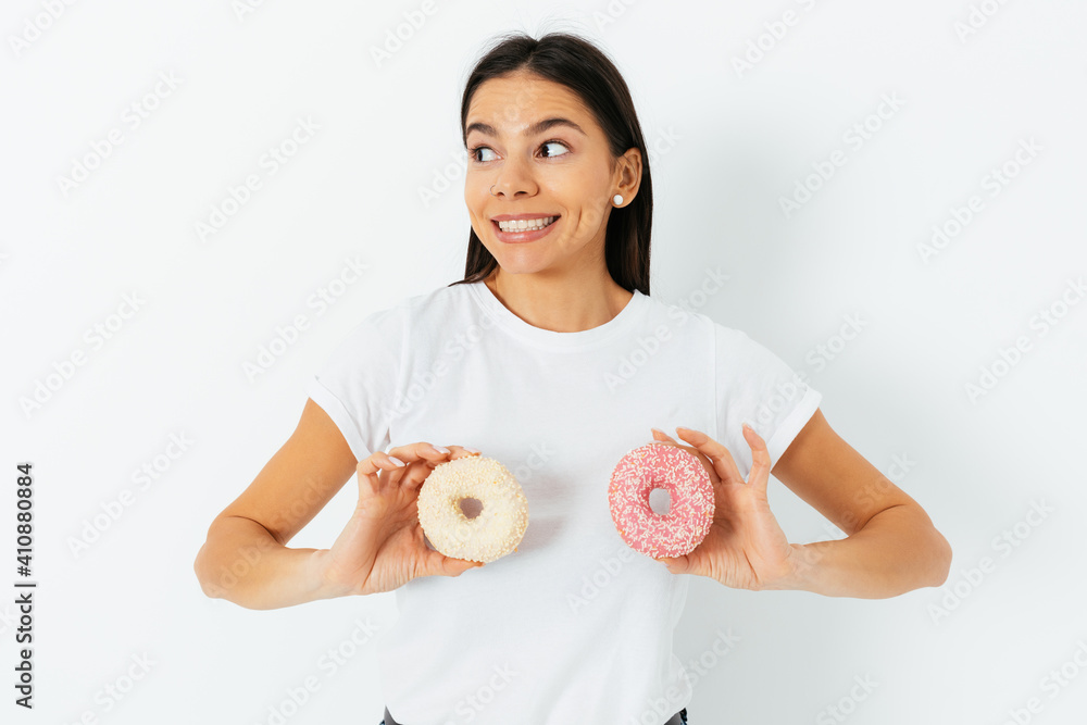 Portrait of smiling young woman holding two donuts at her breasts Portrait of smiling young woman holding two donuts at her breasts