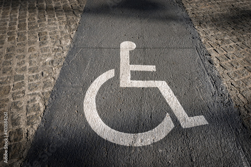 Photography Close-up of a lane reserved for wheelchairs in the city of Barcelona with a white (Accessibility for Persons with Disabilities) symbol painted on the gray concrete