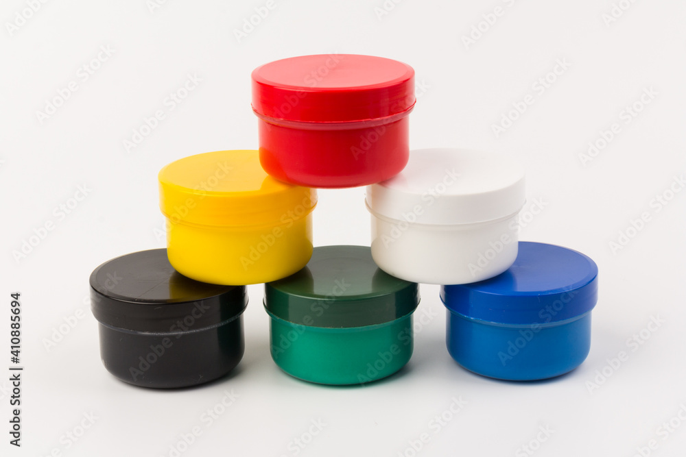 Closed plastic jars with paint of different colors for children's creativity on white background. Paint bottles for art Closed plastic jars with paint of different colors for children's creativity on white background. Paint bottles for art