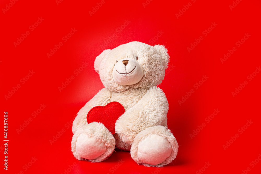 Teddy bear holding a heart on a red background Teddy bear holding a heart on a red background