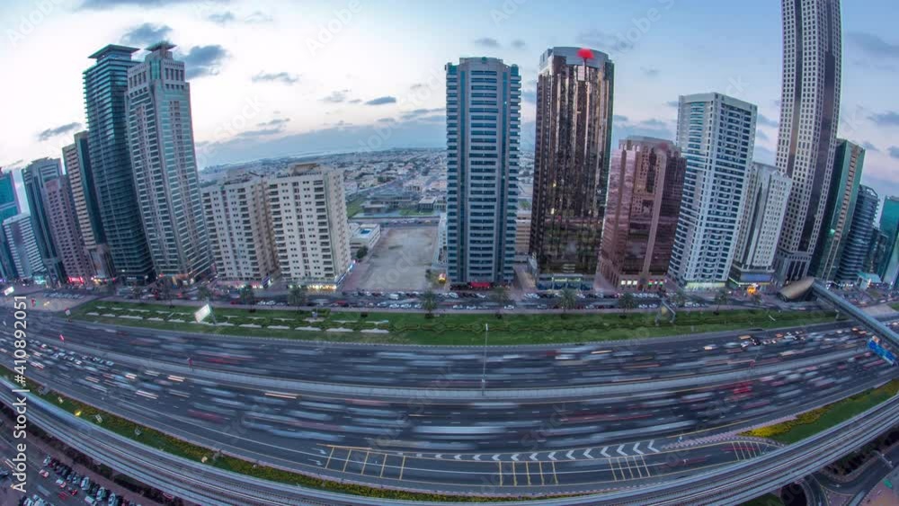 Downtown Dubai towers day to night transition timelapse. Aerial view of Sheikh Zayed road with skyscrapers after sunset. Traffic on the road and metro line. Beautiful cloudy sky. Fisheye lens panorama Downtown Dubai towers day to night transition timelapse. Aerial view of Sheikh Zayed road with skyscrapers after sunset. Traffic on the road and metro line. Beautiful cloudy sky. Fisheye lens panorama