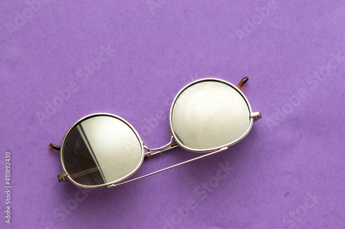 Fashionable sunglasses. gold-colored metal, on a purple background