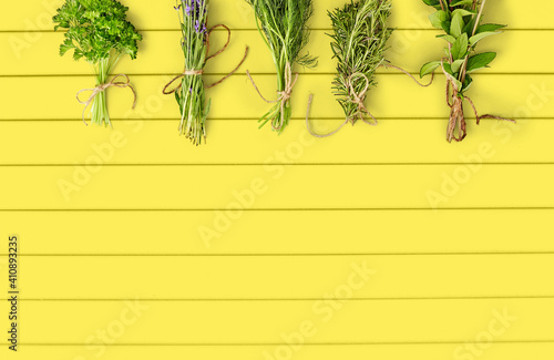 gardening  botany and organic concept - bunches of greens  spices or medicinal herbs over yellow wooden boards background