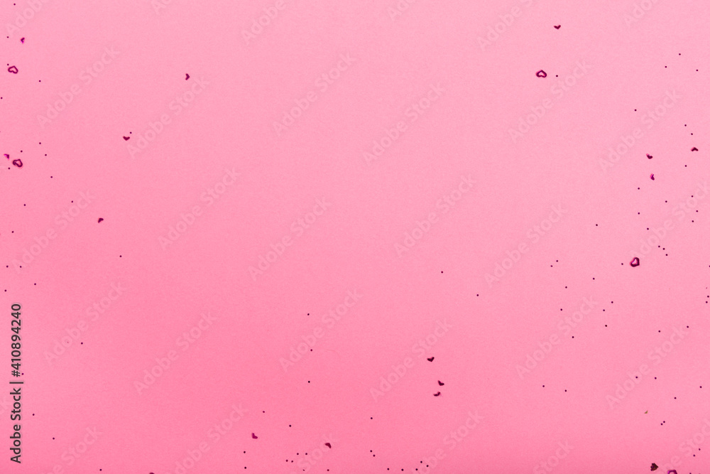 Red heart shaped confetti scattered on pink background