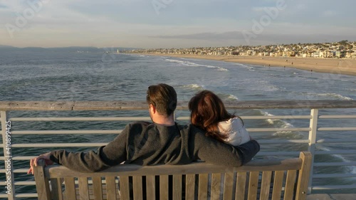 Couple men and woman at Hermosa Beach Pier famous La La Land scenary, enjoing beautiful view of ocean with sun flare photo