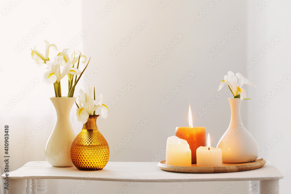 burning candles and spring flowers on wooden shelf in white interior burning candles and spring flowers on wooden shelf in white interior