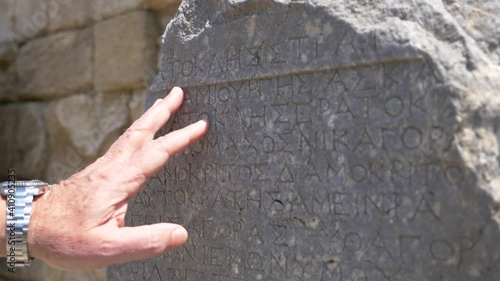 Rhodes Kamiros greece ancient greek writing on a marble surface with the hand of an observer trying to read it 