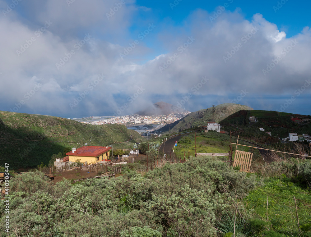 View of Gran Canaria landscape from a hill with Galdar town, Montana de Ajodar, red roof country house and winding road background. Canary island, Spain