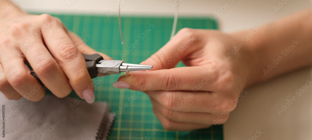 Woman using pliers to adjust malachite gemstones. Craft jewelery making with professional tools. A handmade jeweler process, manufacture of jewellery.