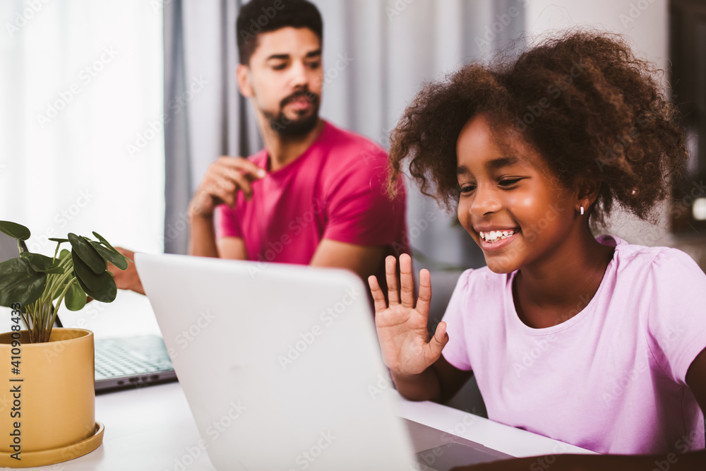 Father using laptop while his daughter is doing homework in the living room. Father using laptop while his daughter is doing homework in the living room.