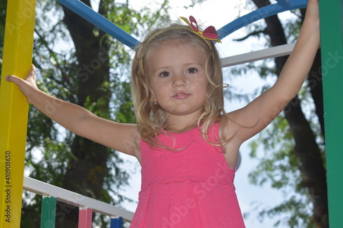 summer beautiful cute little blonde girl  in pink dress is playing on the playground © Тамара Киреева