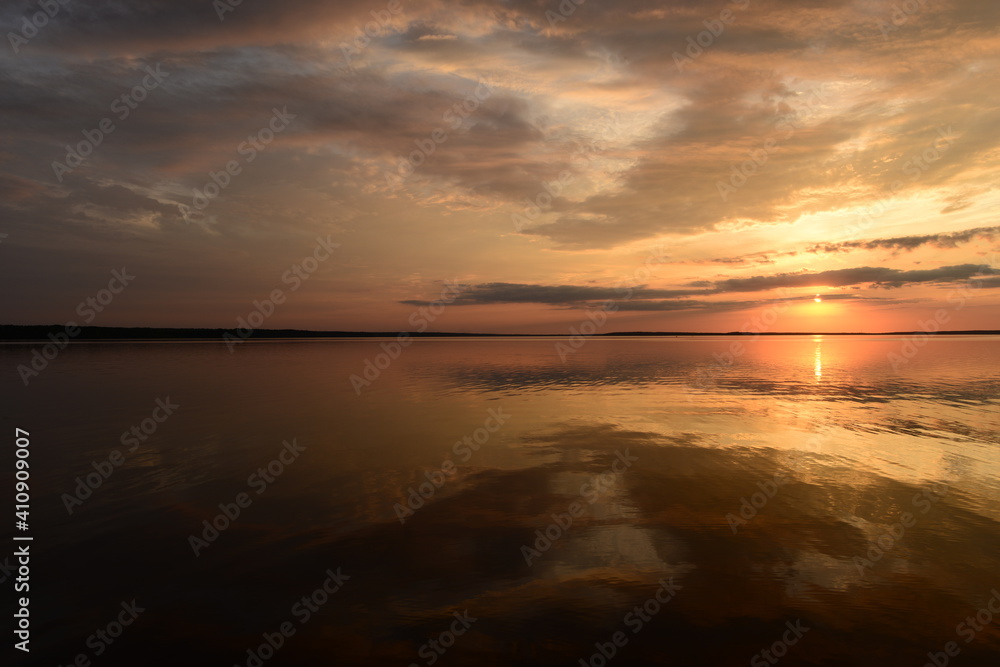 Twilight sky in colorful bright sunlight reflects off on the water surface