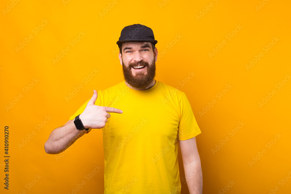 Photo of young bearded man in yellow shirt pointing at him.