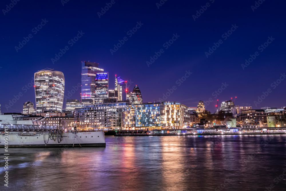 London cityscape at night view at the City of London from across the river Thames, night life in UK capital city, lots of lights and reflections in the water and beautiful sky with long exposure photo